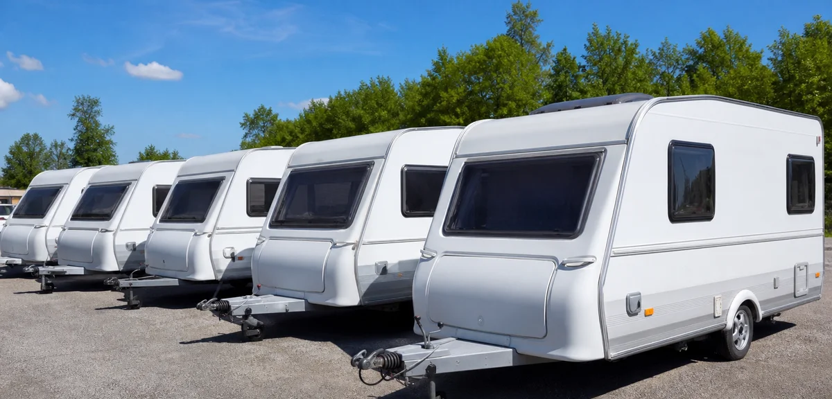 屋外の販売店に並ぶ複数の中古のキャンピングトレーラー、白い車体、晴れた日、写実的、文字なし